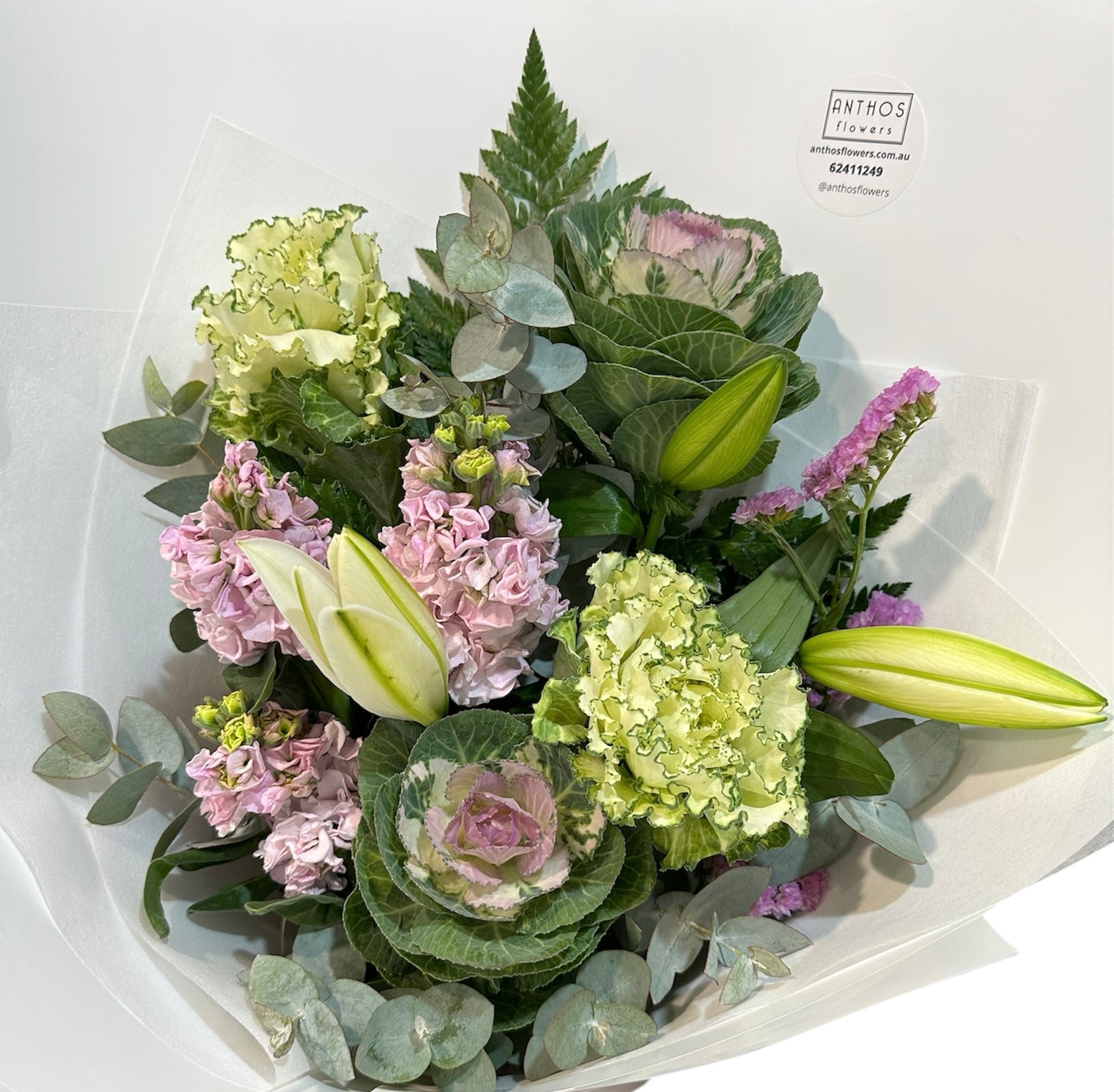 Bouquet of flowers with green and pink hues on a white background, featuring the brand 'ANTHOS'.